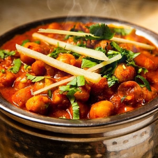 Steaming bowl of chana masala, garnished with fresh cilantro and ginger strips.