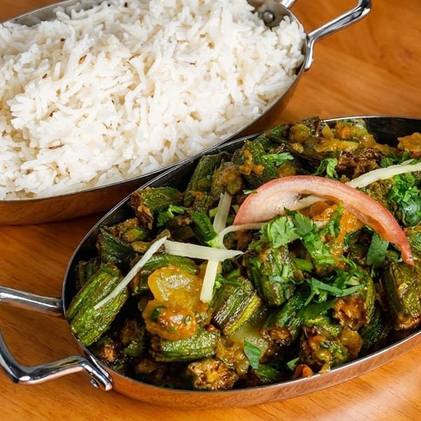 Indian dish of bhindi masala with okra, tomato, and cilantro, served with a side of basmati rice.